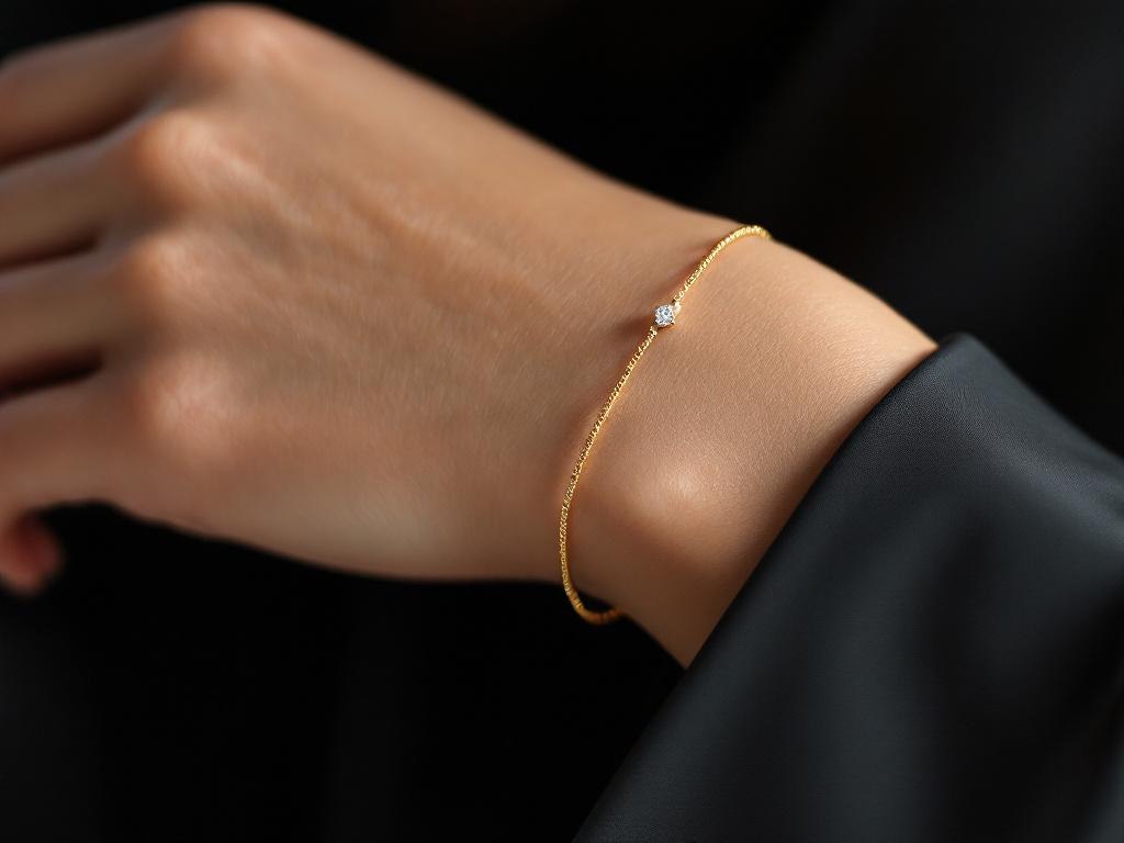 delikatna złota bransoletka z małym diamentem na nadgarstku